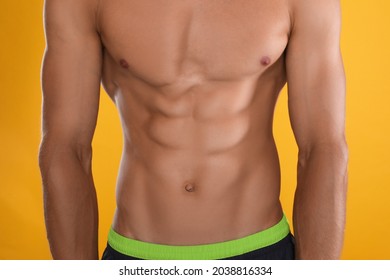 Shirtless man with slim body on yellow background, closeup