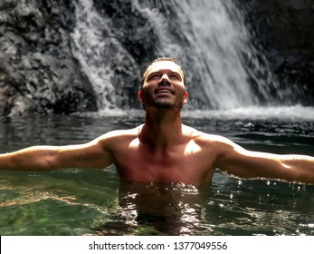 Shirtless man standing at lake with waterfall in Cape Verde island - Powered by Shutterstock