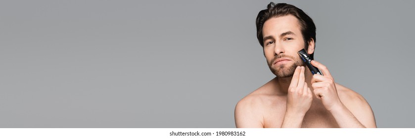 shirtless man using electric razor isolated on grey, banner - Shutterstock ID 1980983162