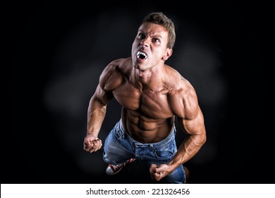 Shirtless Muscle Man With Pointed Teeth Transforming Into Werewolf In Studio With Black Background