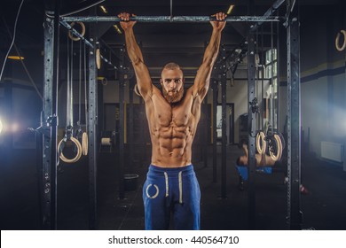 Shirtless muscular bearded male doing exercises on horizontal bar in a gym club. - Powered by Shutterstock