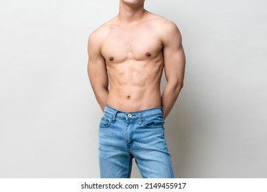 Shirtless muscular male model body on gray isolated background in light studio