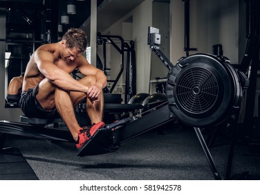Shirtless muscular male training hard in a gym club.