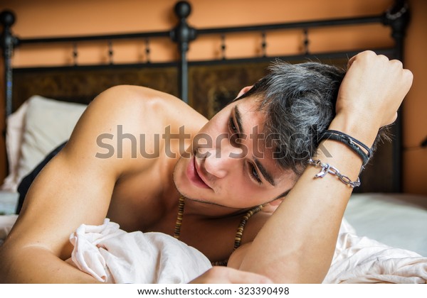 Shirtless sexy male model lying alone on his bed in his bedroom ...