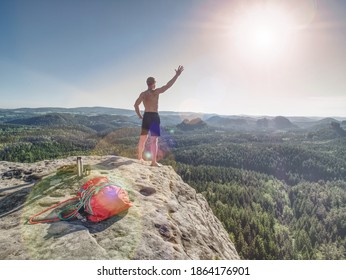 Shirtless Sportsman Take Off Backpack And Rope On Top Of The Mountain And Raised Arms To Greeting Nature. Backpack And Climbing Equipment On Mountain Summit.