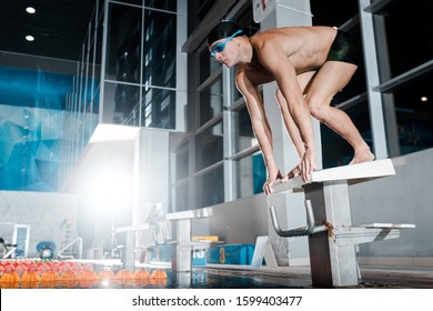 Shirtless Swimmer Standing In Starting Pose On Diving Block