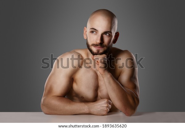 shirtless turkish man think about\
idea leaning with elbow on table and having his fist on his chin \
