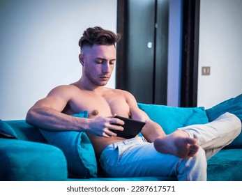 Shirtless young athletic man reading on ebook reader - Powered by Shutterstock