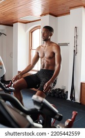 Shirtless Young Black Man Cycling On Exercise Bike At The Gym