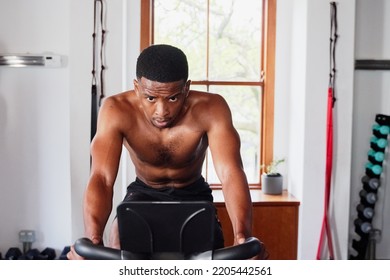 Shirtless Young Black Man Doing Cardio Workout On Exercise Bike At The Gym