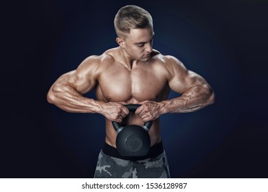Shirtless young caucasian athlete with muscular body exercising crossfit with kettle bell on black background Intensive cross training Shot at studio on black background.