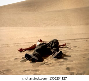 Shirtless Young Man Lying On His Back In A Dandy Desert.