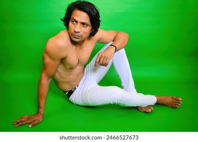 Shirtless Young man thinking pose, Thoughtfully men sitting on floor, Indian, Person pensive, Looking away, Long hair, and white pant, Seated on a green background, in a thoughtful posing, 30s guy. - Powered by Shutterstock