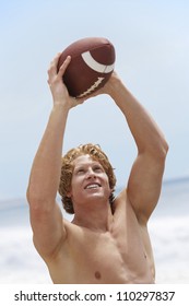 Shirtless Young Man Throwing American Football Ball On Beach