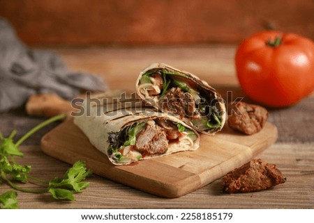 Shish kabab, kebab sandwich. turkish and Arabic Traditional Ramadan Adana Kebab Roll Wrap serving with yogurt, aubergine salad and hot pepper pickles on rustic wooden background.
