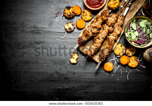 Шашлык на шампуре с овощами на гриле и свежим салатом. На черном ... Шашлык на Шампуре