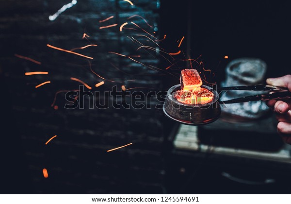 Shisha hookah with red hot coals. Sparks from\
breathe. Modern hookah with coconut charcoal for relax and shisha\
smoke. Hookah and sparks from coals. Another view. Shisha,\
spark,spark, hookah\
sparks.