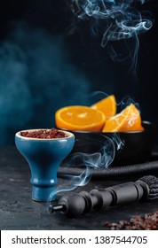 Shisha Smoking hookah in a blue glossy bowl on the background of a bowl with sliced oranges. Vertical.