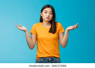 Shit happens. Indifferent absolutely careless female student not care how accident happened shrugging, look camera questioned unaware, hard answer, clueless how deal situation, stand blue background