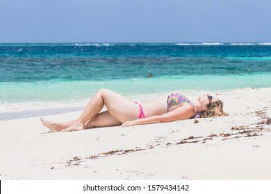 Shoal Bay / Antigua - August 2017: Brunette Woman In Bikini Laying On The White Sand Beach Of Shoal Bay Antigua 