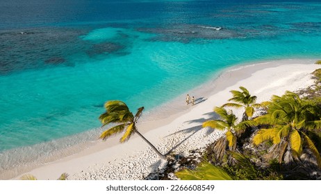 shoal bay east, Anguilla. Couple walking on the beach. Beautiful beach with turquoise sea. Crystalline waters of white sand, with plenty of shade from coconut trees. The best beach in the Caribbean.