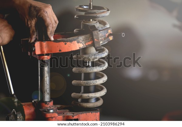 Shock Absorber ,Shock maintenance,Shock\
replacement,Car garage technician using spring compression tool to\
repair damaged shocks