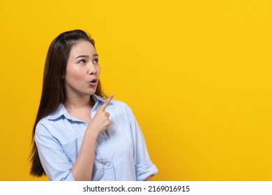 Shock Asian Young Woman Pointing Finger Up With Surprise Facial Expression.