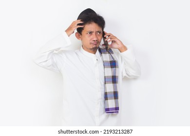 Shock And Confused Asian Muslim Man Using Mobile Phone Isolated On White Background