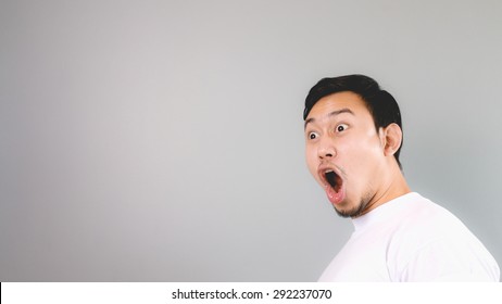 Shock Face On Empty Copyspace. An Asian Man With White T-shirt And Grey Background.