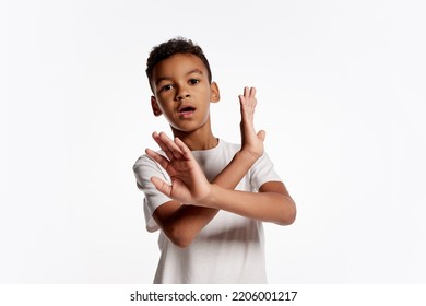 Shock, Scare. Half-length Portrait Of African Little Boy In White Tee Expressing Emotions And Gesturing Stop Sign Isolated Over White Background. Kids Emotions, Facial Expressions, Kids Fears Concept