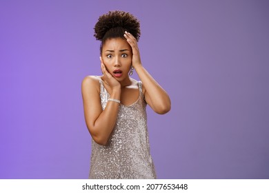 Shocked afraid timid insecure african-american woman in silver trendy dress panic widen eyes frightened look camera touch head terrified anxiously staring gasping speechless shook, blue background