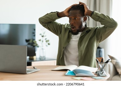 Shocked African American Man Looking At Laptop Screen, Grabbing His Head In Terror, Making Mistake Or Missing Project Deadline. Black Guy Having Remote Work Stress