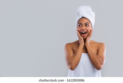 Shocked african woman in towels touching her cheeks and looking at free space, good offer at spa - Powered by Shutterstock