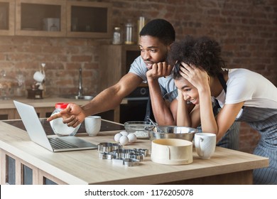 Shocked african-american couple baking with recipe on laptop in loft kitchen - Powered by Shutterstock