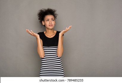 Shocked african-american woman with arms up in air in full disbelief. Surprised girl portrait, gray background. Omg, wtf, human emotions concept
