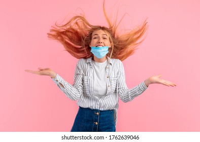 Shocked, Agitated Young Woman In A Medical Protective Mask On Her Face, Screaming With Delight, Standing Isolated Against A Pink Background