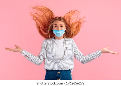 Shocked, Agitated Young Woman In A Medical Protective Mask On Her Face, Screaming With Delight, Standing Isolated Against A Pink Background