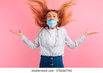 Shocked, Agitated Young Woman In A Medical Protective Mask On Her Face, Screaming With Delight, Standing Isolated Against A Pink Background