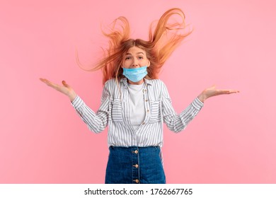 Shocked, Agitated Young Woman In A Medical Protective Mask On Her Face, Screaming With Delight, Standing Isolated Against A Pink Background