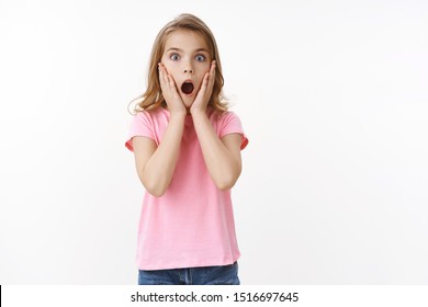 Shocked Amazed Cute Little Kid, Blond Teenage Girl, Gasping Amazed Speechless Stare Camera, Touch Face From Shock, Look Scared, Drop Jaw Wondered, Standing Ambushed White Background