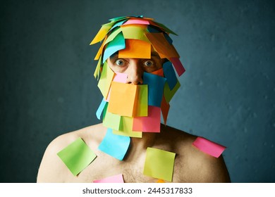 Shocked amazed man with colorful sticky notes all over his face and body over gray background - Powered by Shutterstock