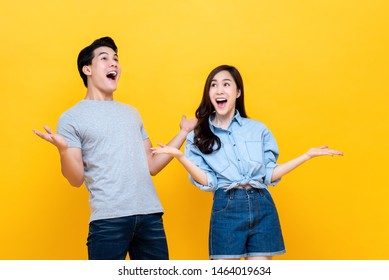Shocked Amazed Young Man And Woman With Open Palms And Mouth Against Yellow Studio Background