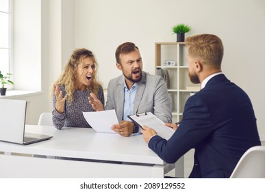 Shocked And Angry Married Couple Receives Bad News From Bank Employee Or Credit Broker. People At Meeting At Bank Argue After Receiving Notice Of Balance Of Debt In Bank Account. Bankruptcy Concept.