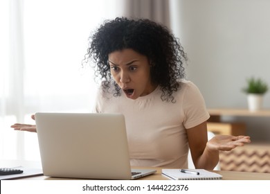 Shocked angry stressed african black woman customer looking at laptop screen feel bad surprise annoyed reading online news frustrated with stuck computer problem website error sit at home office desk - Shutterstock ID 1444222376
