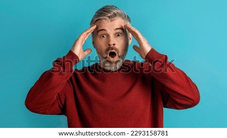 Shocked appalled middle aged grey-haired man wearing casual gesturing on blue background, touching his head and exclaiming, panorama. Human gestures and emotions concept