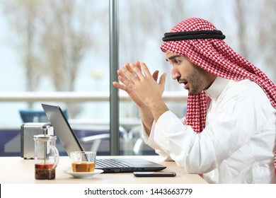 Shocked Arab Man Checking Laptop Content Sitting In A Coffee Shop