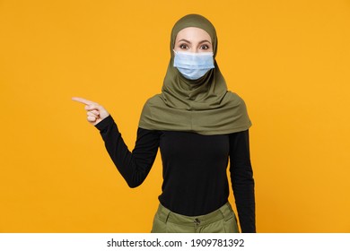 Shocked arabian muslim woman in hijab green clothes sterile face mask to safe from coronavirus virus covid-19 pointing finger aside isolated on yellow background. People religious lifestyle concept - Powered by Shutterstock