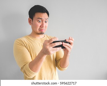 Shocked Asian Man Plays Mobile Game In His Smartphone.