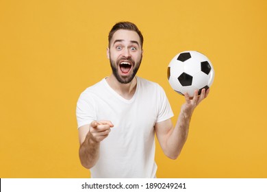 Shocked Bearded Man 20s Football Fan In White T-shirt Isolated On Yellow Background. People Sport Family Leisure Concept. Cheer Up Support Favorite Team With Soccer Ball Point Index Finger On Camera