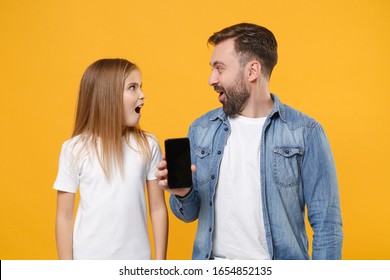 Shocked Bearded Man Have Fun With Child Baby Girl. Father Little Kid Daughter Isolated On Yellow Background. Love Family Day Parenthood Childhood Concept. Hold Mobile Phone With Blank Empty Screen